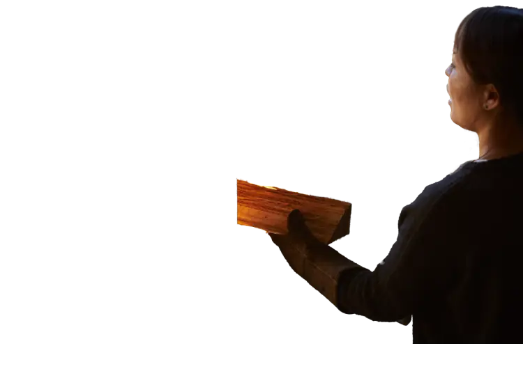 薪ストーブに薪を焚べる人の画像