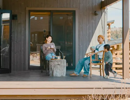 ウッドデッキの椅子に座ってコーヒーを飲んでくつろぐ体験者の画像